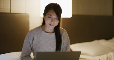 Kadınlar dizüstü bilgisayarda çalışır ve geceleri yatakta otururlar.