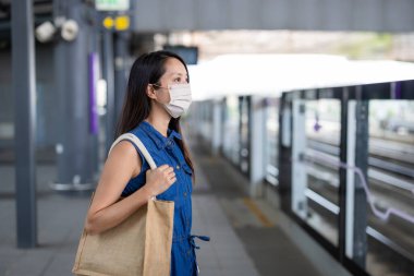 Woman wear face mask and wait for the train