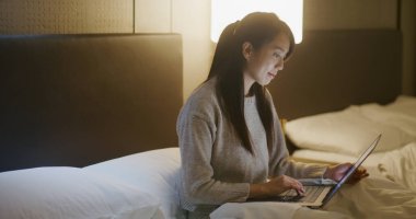 Kadın otel odasında bilgisayarla çalışıyor.