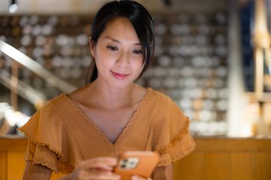 Kadın kahve dükkanında cep telefonu kullanıyor.