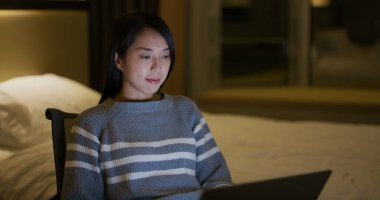 Woman use laptop computer at night in bedroom