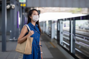 Woman wear face and wait for the train
