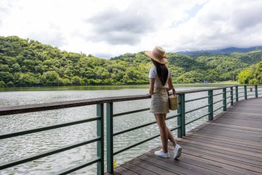 Asian woman walk on the lakeside wooden path