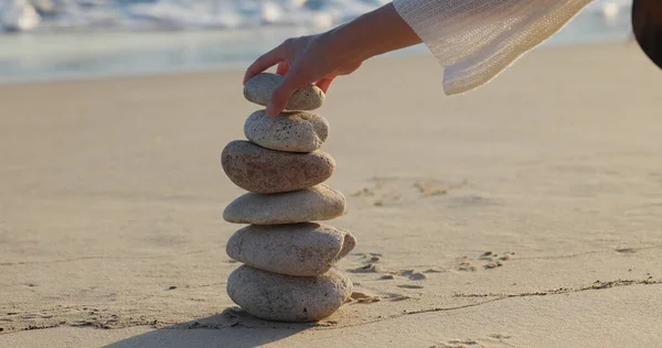 Woman build zen stone tower with pebble stone