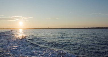Back of the ship cruising over the sea at sunset time