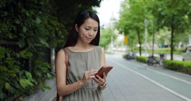 Woman use mobile phone walk at park