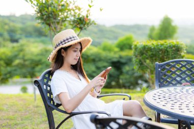 Woman use mobile phone and sit on outdoor chair