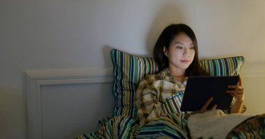 Woman watch on tablet computer on bed at night