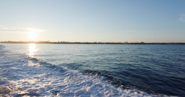Back of the ship cruising over the sea at sunset time
