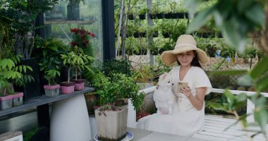 Bir kadın açık hava bahçesinde köpeğiyle cep telefonu kullanıyor.