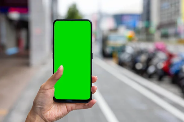 Woman hold with green screen cellphone at street
