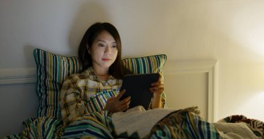 Woman read on tablet computer and lying on bed at night