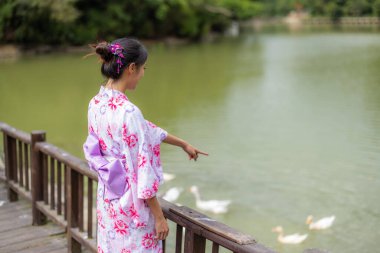 Asyalı kadın kırsal kesimdeki göl ile Japon yukata giyiyor.
