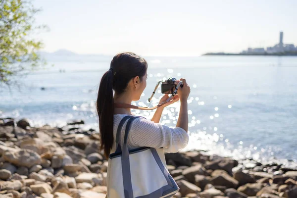 女性は海のビーチを訪問し 写真を撮るためにデジタルカメラを使用します — ストック写真