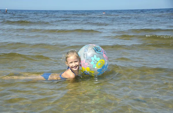 Het meisje baadt met een bal in water, bij Zeekust in jurmala (la — Stockfoto