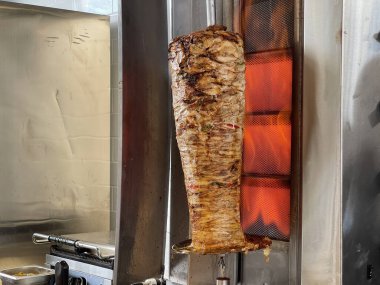 Orta boy bir ateşte dönen bir tükürüğü ısıtmak ve shawarma için et pişirmek (donör, giros, doner kebap).