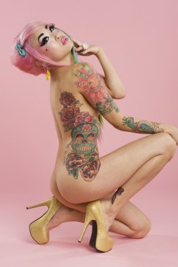 pembe bir arka plan üzerinde genç bir dövmeli kadın tam uzunlukta