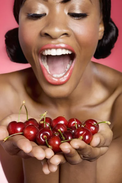Cheerful young woman looking at cherry in her hands — Stock Photo, Image