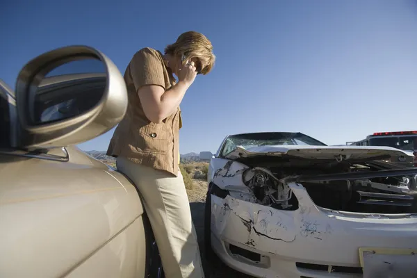 Young woman using mobile phone by car wreckage — Stock Photo, Image