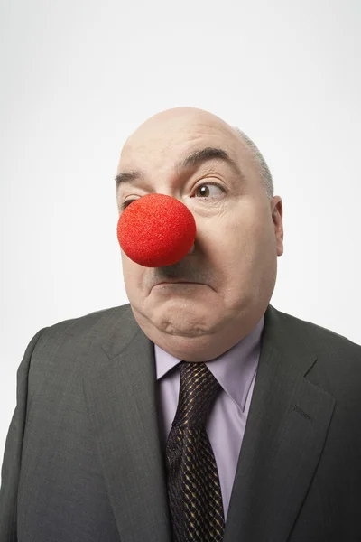 Affärsman bära clown näsa rynkar pannan — Stockfoto