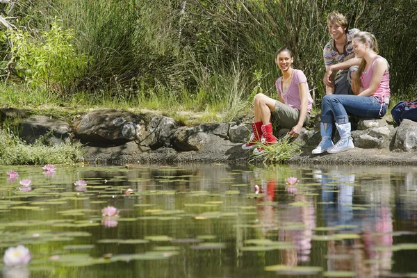 Drie wandelaars zitten door meer — Stockfoto