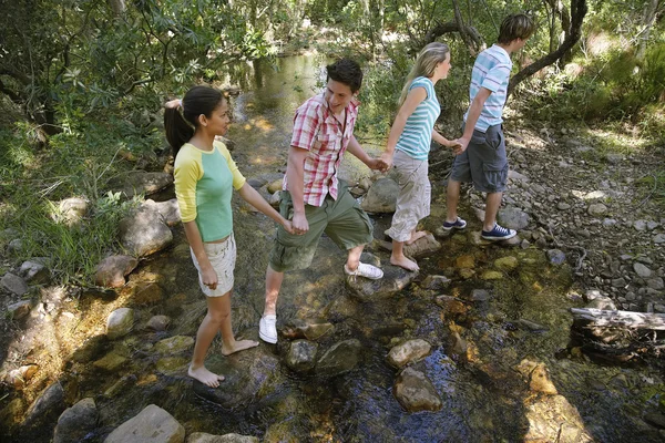 Friends Crossing Stream While Holding Hands — Stock Photo, Image