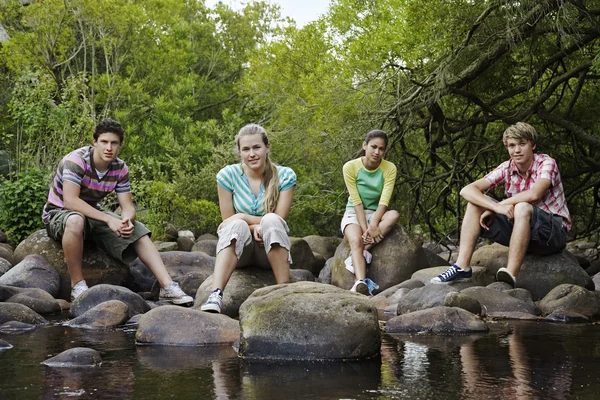 Amigos sentados en piedras por Forest River — Foto de Stock