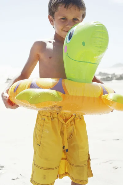 Menino brincando com tubo flutuante na praia — Fotografia de Stock