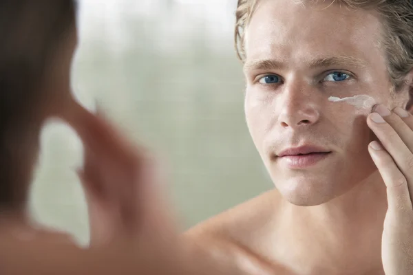 Uomo che applica crema viso — Foto Stock