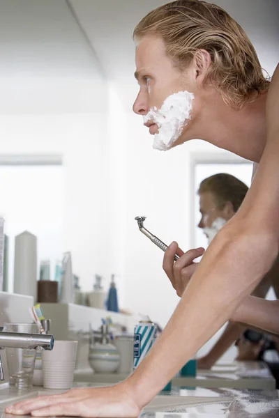 Genç adam banyoda tıraş oluyor. — Stok fotoğraf