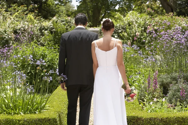 Casal recém-casado caminhando no jardim — Fotografia de Stock