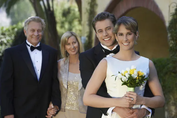 Novia y novio con los padres en segundo plano — Foto de Stock