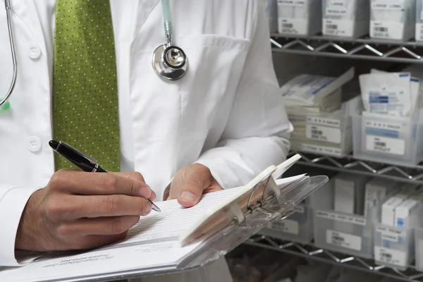 Doctor masculino escribiendo en portapapeles — Foto de Stock