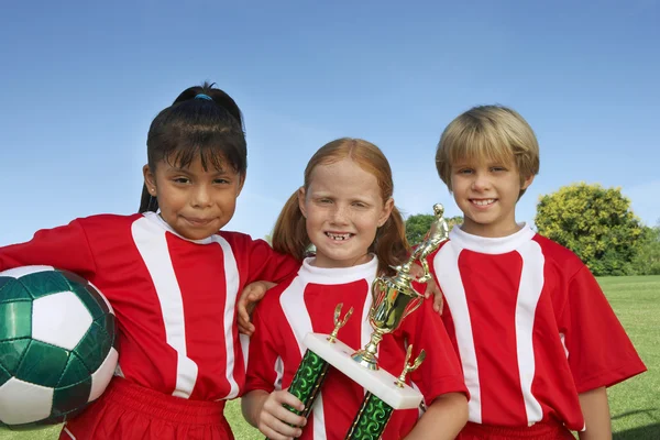 Děti s fotbalovým míčem a trophy — Stock fotografie