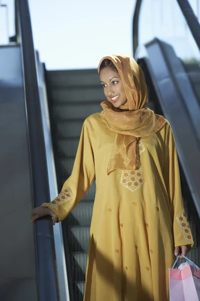 Mulher muçulmana em pé na escada rolante — Fotografia de Stock