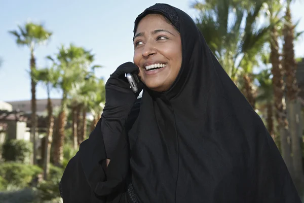 Mujer musulmana en negro hijab usando el teléfono celular —  Fotos de Stock