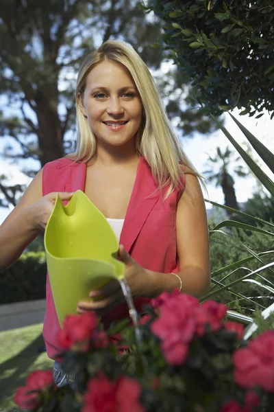 Jeune femme arrosage plante — Photo