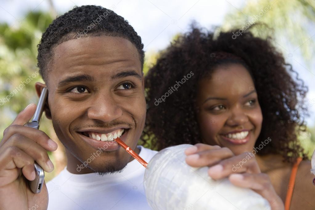 Couple With Man On Call Sipping Milkshake