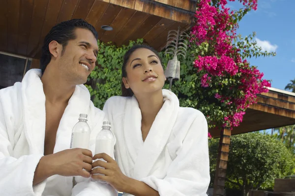 Par i badrockar håller vattenflaskor — Stockfoto