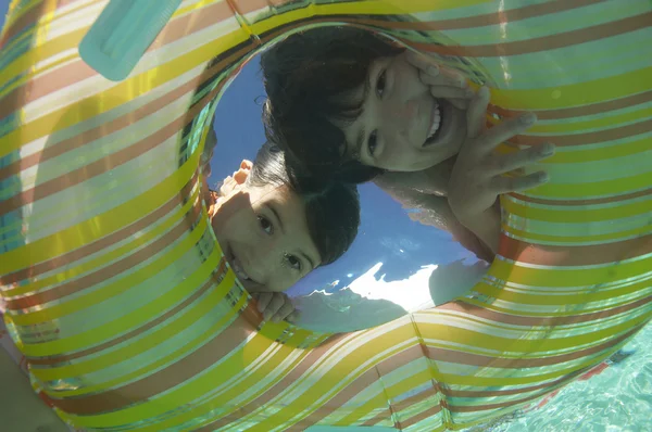 Brother and Sister Looking Through Inflatable Ring — стоковое фото