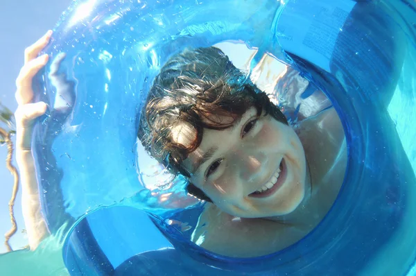 Garçon regardant à travers l'anneau gonflable dans l'eau — Photo