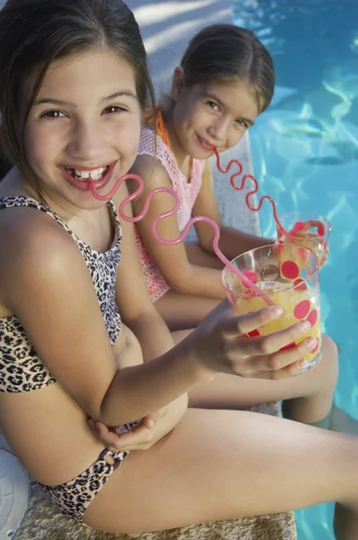 Hermanas bebiendo jugo junto a la piscina —  Fotos de Stock