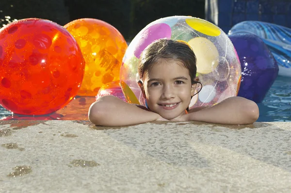 Meisje in zwembad met strand ballen — Stockfoto