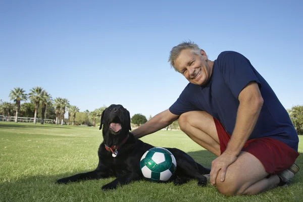 Старший чоловік з собакою і футбольним м'ячем в парку — стокове фото