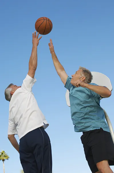 Мужчины играют в баскетбол против голубого неба — стоковое фото