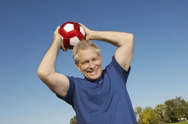 Starší muž vrhací fotbalový míč — Stock fotografie