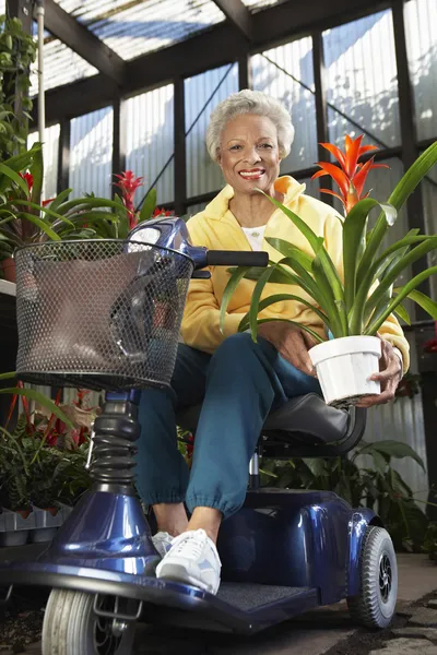 Mujer con discapacidad en la vespa del motor con la planta en el jardín botánico — Foto de Stock