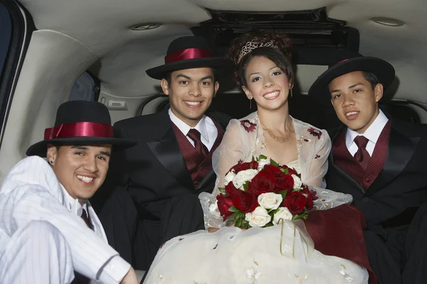 Quinceanera sitzt mit drei männlichen Freunden in Limousine — Stockfoto