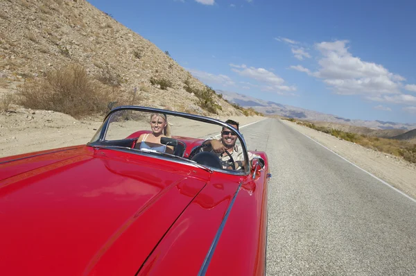 Pareja en coche clásico en la carretera del desierto — Foto de Stock