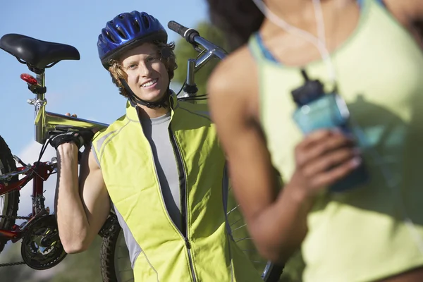 Manlig cyklist bär cykel med kvinna i förgrunden — Stockfoto